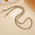 Detail of hand-woven black and white crossbody chain strap with gold metal lobster clasps - Black