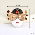 Detail view of a vintage mask charm with red rhinestones and white enamel finish - Gold Champagne Ball Mask (D3314)