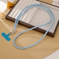 Close-up of sky blue rhinestone phone strap with silver clasp on a jewelry tray - Blue