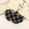 Macro shot of checkered heart bag charm with silver buckle and pearl bead detail - Black Plaid