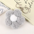 Vue détaillée du porte-clés fleur en peluche grise avec un centre blanc moelleux - Gris