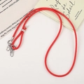 Detail of red braided PU leather phone strap with silver lobster clasps and slider buckle - Red