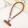 Close-up of brown braided PU leather phone wrist strap with silver metal ring and T-shaped patch - Light Brown