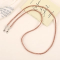 Close-up of rose gold mesh chain with lobster clasps on elegant fabric background - Champagne
