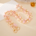 Pink and cream woven plush metal chain strap with dual gold rings on a warm background - Pink