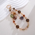 Detail of leopard print plush balls and bohemian beaded charms on a gold keychain - Brown