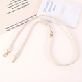 Dettaglio tracolla regolabile in pelle beige chiaro con moschettoni in oro lucido - Bianco