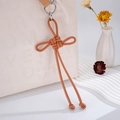 Brown braided PU leather Ruyi knot bag charm with silver ring on a white textured handbag - Brown