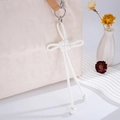 Detail of white woven PU leather knot charm hanging on a stylish cream handbag - White