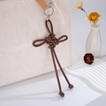 Dettaglio di ciondolo per borsa in pelle PU intrecciata marrone con lunghe nappe e anello - Ciondolo Nodo Ruyi (K2728) / Caffè Scuro