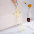 Dettaglio di un nodo cinese artigianale in pelle giallo chiaro su una borsa beige - Ciondolo Nodo Ruyi (K2727) / Giallo