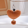 Detailed close-up of brown plush heart keychain with silver clip on a tree branch - Brown