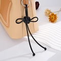 Detail of leather bag charm featuring hand-woven knot and premium stitching details - Black