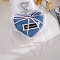 Detail of blue denim heart charm with white lace, pink bow, and silver heart clasp - Blue