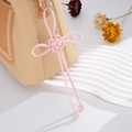 Dettaglio del ciondolo a nodo portafortuna rosa intrecciato a mano su borsa beige - Ciondolo Nodo Auspicabile (K2710) / Rosa