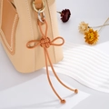 Dettaglio della nappa a nodo in pelle intrecciata su una borsa patchwork crema e marrone - Ciondolo Nodo Auspicabile (K2709) / Marrone