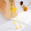 Dettaglio del ciondolo a nodo intrecciato giallo su borsa in pelle bicolore e metallo - Ciondolo Nodo Auspicabile (K2708) / Giallo