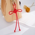 Dettaglio di un nodo cinese rosso fatto a mano attaccato a una borsa in pelle chic - Ciondolo Nodo Auspicabile (K2707) / Rosso
