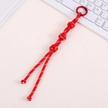 Macro shot of red hand-woven Chinese knot bag pendant with metal ring buckle - Red