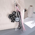 Dettaglio del ciondolo a cuore con nastro rosa e chip da poker su borsa beige - Nero