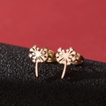 Macro shot of rose gold dandelion stud earrings on black leather with red background - Rose Gold