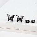 Macro shot of matte black hollow butterfly earrings on white textured surface - 268 Black