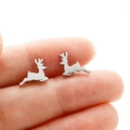 Macro shot of silver deer stud earrings on a fingertip showing the petite size - Steel