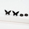 Detailed close-up of matte black butterfly stud earrings on a textured stone display pedestal - 270 Black