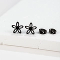 Detail van minimalistische zwarte holle bloemoorbellen met vlindersluiting op steen - Vijfbladige Bloem (154) / Zwart