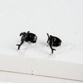 Détail de boucles d'oreilles sirène noires sur une surface en pierre texturée - Forme de Sirène (397) / Noir