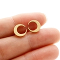 Macro shot showing size of golden crescent moon stud earrings held on a finger - Gold