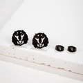 Detailed view of black hollow-out Shar Pei puppy stud earrings on a white stone pedestal - Lion Head Shape (687) / Black