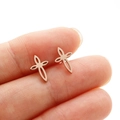 Gros plan de boucles d'oreilles croix en or rose sur un doigt montrant les détails - Or rose