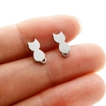 Close-up of minimalist silver cat silhouette stud earrings held on finger for size - Steel Color Cat
