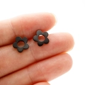 Orecchini a perno minimalisti a fiore nero con cinque petali mostrati sulla punta del dito - Stile Fiore Cavo 309 / Nero