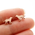 Detail view of rose gold dog silhouette stud earrings held on a fingertip for size - Dog Style (364) / Rose Gold