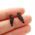 Macro shot of minimalist black hollow bird stud earrings in stainless steel on finger - Bird (373) / Black