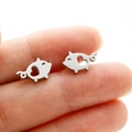 Detailed view of silver stainless steel pig stud earrings with heart cutout held in hand - Pig (371) / Steel