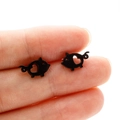 Close-up of cute black pig-shaped stud earrings with heart cut-out detail - Black