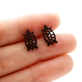 Primer plano de pendientes de tortuga marina negros minimalistas en la mano - Estilo Tortuga (367) / Negro