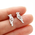 Macro view of silver parrot stud earrings held by hand to show compact product size - Bird (373) / Steel