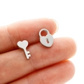 Close-up of mini asymmetric heart key and lock studs held between fingers for scale - Steel