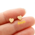 Minimalist 4mm golden heart stud earrings with polished finish shown on a fingertip - Small Style / Gold