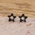 Detailed macro shot of black geometric hollow star earrings on a pink rock base - Hollow Star Style (898) / Black