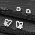 Polished stainless steel heart and flower stud earrings on a dark slate background - Steel