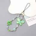 Détail du bijou de téléphone perlé avec papillon vert, étoiles et perles argentées - Vert