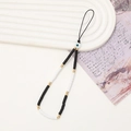 Dettaglio del cinturino per telefono Evil Eye fatto a mano con perline heishi bianche e nere - Stile Ceramica Morbida Bianco e Nero (K677)