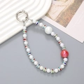 Dettaglio del cinturino per cellulare con perle bianche e distanziatori con strass - Bianco + Rosso