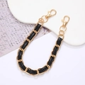 Detalle de la elegante cadena de cuero negro entrelazada con metal dorado y cierres - Cadena de mano / Negro