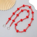 Detail of red plush balls and polka dot beads on a crossbody phone chain strap - Red